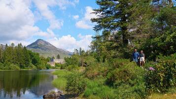 A scenic view of a lake with a mountain in the background, surrounded by lush greenery and a building with a traditional architectural style.