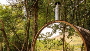 A wooden barrel structure with a metal chimney, surrounded by trees and a body of water. - Ballynahinch Castle Hotel (Ballynahinch)