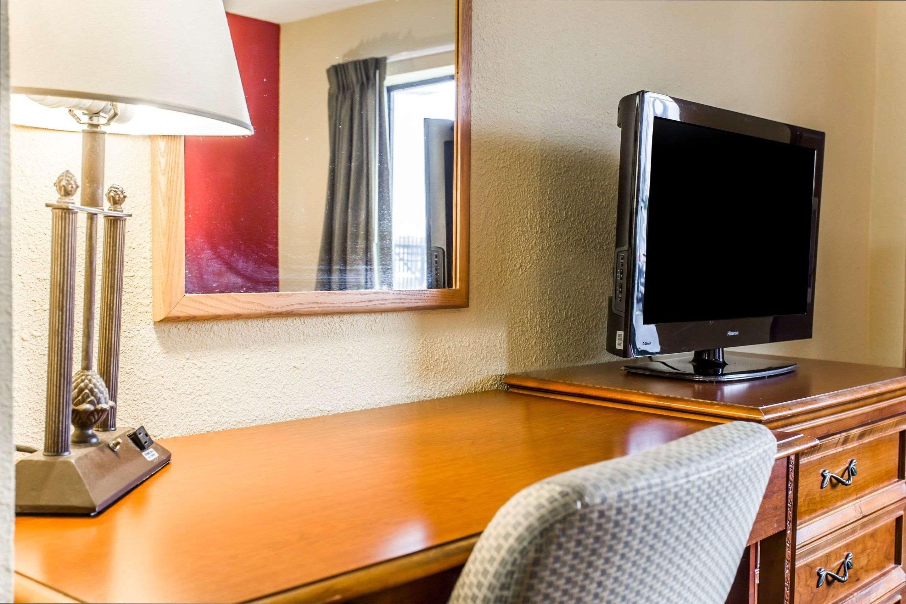 Een hotelkamer met een houten bureau, een televisie, een lamp en een spiegel.