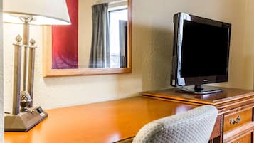 Een hotelkamer met een houten bureau, een televisie, een lamp en een spiegel.