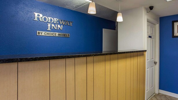 A reception desk with a blue wall and a sign that reads "RODEWAY INN BY CHOICE HOTELS". - Rodeway Inn Charlotte (Charlotte)