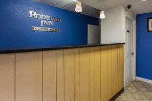 A reception desk with a blue wall and a sign that reads "RODEWAY INN BY CHOICE HOTELS". - Rodeway Inn Charlotte (Charlotte)