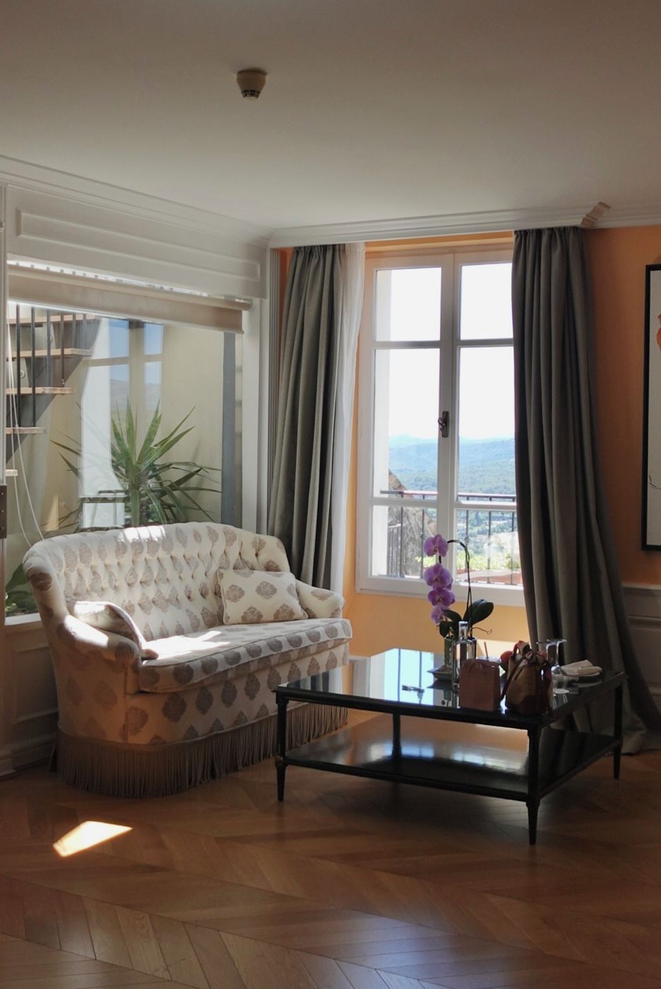 A living room with a sofa, a coffee table, and a view through a window.