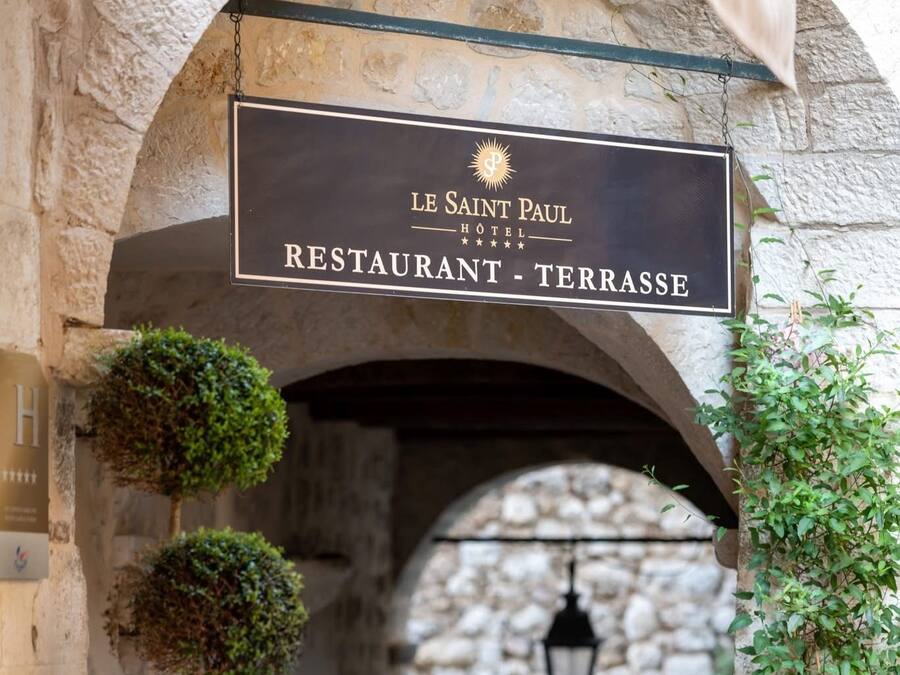 Entrada para o Hotel Restaurante Le Saint Paul - Terrasse, com arcos de pedra e lanternas penduradas.