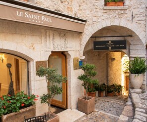 Un bâtiment en pierre avec une enseigne indiquant « LE SAINT PAUL » et une entrée portant l’inscription « BEAUBIA - TERRASSE - CAVE À VIN ».