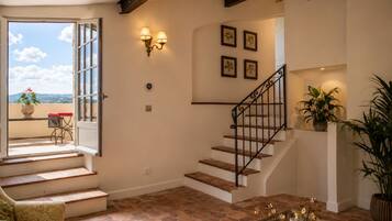 A staircase with a black railing, a potted plant on the landing, and a view of the outside through an open door.