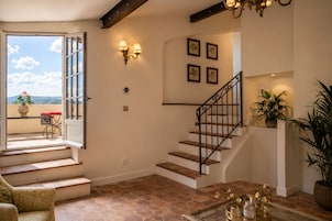 A staircase with a black railing, a potted plant on the landing, and a view of the outside through an open door.