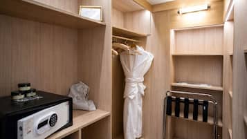 Quarto de hotel com guarda-roupa de madeira, roupão pendurado em um suporte, porta-toalhas e uma pequena mesa com micro-ondas.