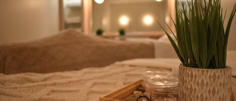 A cozy bedroom with a bed, a bedside table with a potted plant, and a tray with decorative items.