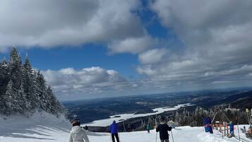 A snowy ski slope with skiers and a clear sky.
