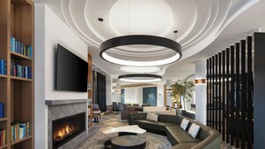 A modern living room with a fireplace, a sectional sofa, and a flat-screen TV mounted on the wall. - Le Westin Tremblant (Mont-Tremblant)