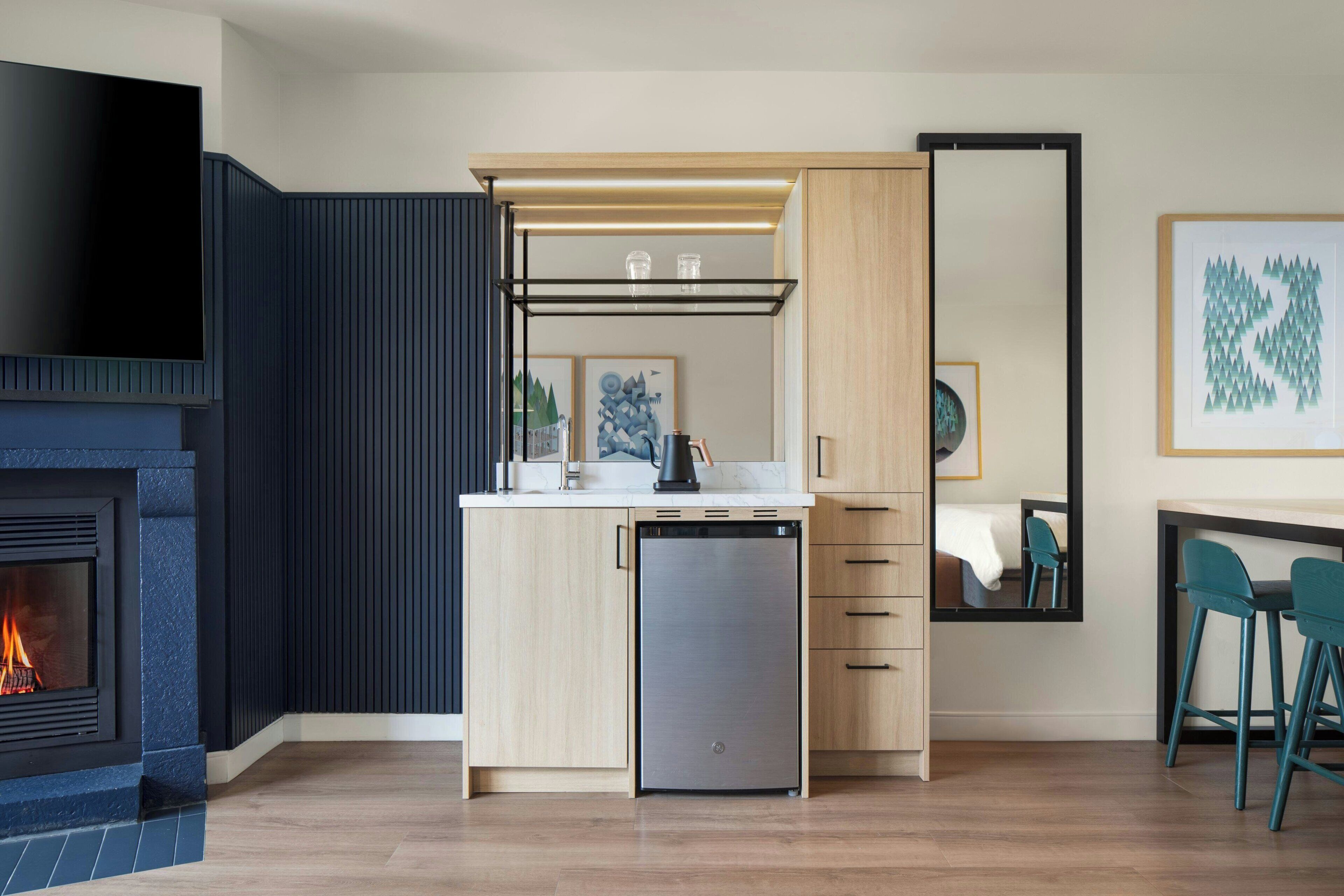A modern kitchen with a built-in dishwasher, a flat-screen TV, and a fireplace.