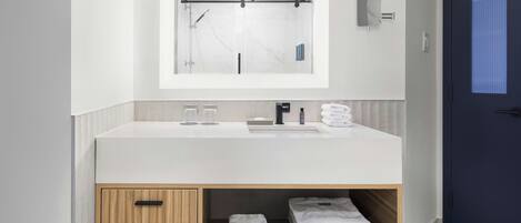 A modern bathroom with a white sink, mirror, and towel storage.