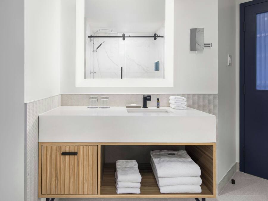 A modern bathroom with a white sink, mirror, and towel storage.