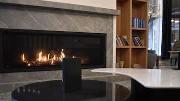 Ein modernes Wohnzimmer mit Kamin, einem runden schwarzen Couchtisch und einer Bücherwand voller Bücher.