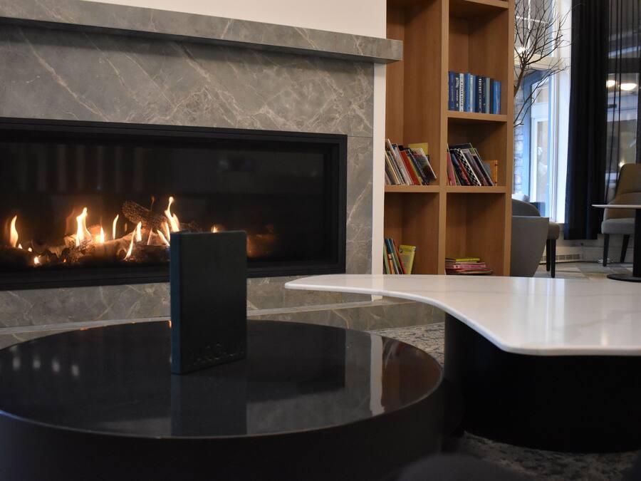 Ein modernes Wohnzimmer mit Kamin, einem runden schwarzen Couchtisch und einer Bücherwand voller Bücher.