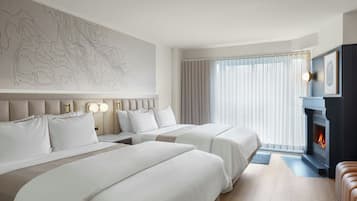A hotel room with two beds, a fireplace, a large window with curtains, and a wall with a map design.