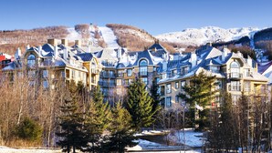 A hotel with multiple buildings, a ski slope in the background, and snow-covered ground. - Le Westin Tremblant (Mont-Tremblant)