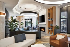 Una sala de estar moderna con chimenea, televisor grande y una zona de estar con sofás y sillones.