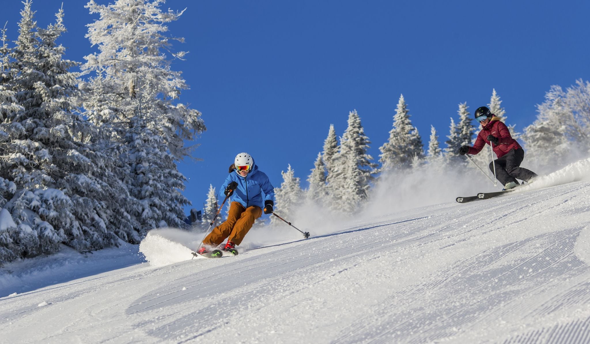 A snowy ski slope with two skiers.