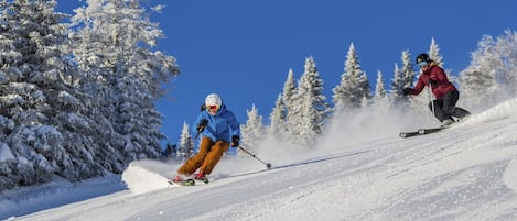 A snowy ski slope with two skiers.