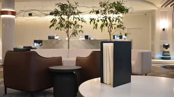 Un vestíbulo moderno con mostrador de recepción, zona de estar y una planta grande.