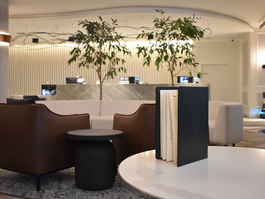 Eine moderne Lobby mit einer Rezeption, einer Sitzecke und einer großen Pflanze.