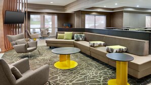 A hotel lobby with a sectional sofa, armchairs, and a small table.