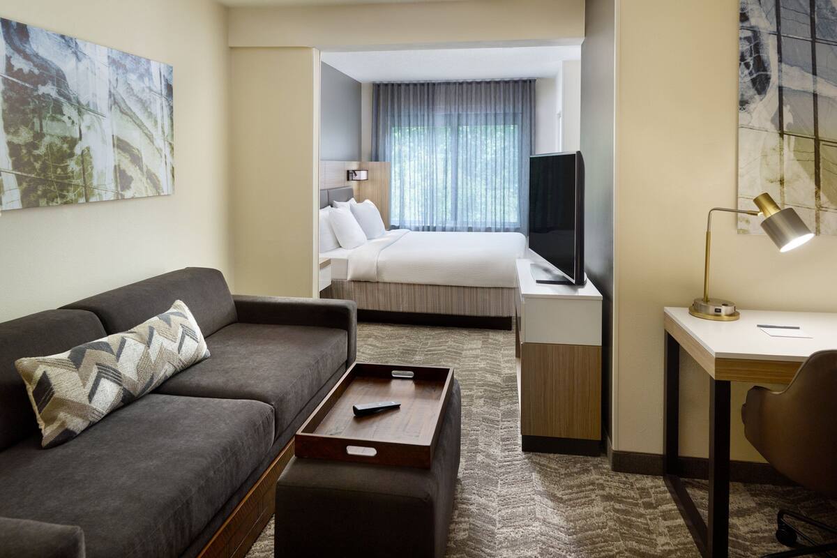 Una habitación de hotel con sofá, escritorio, cama y televisor.