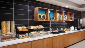A buffet area with various food items, including pastries and containers of cereal.