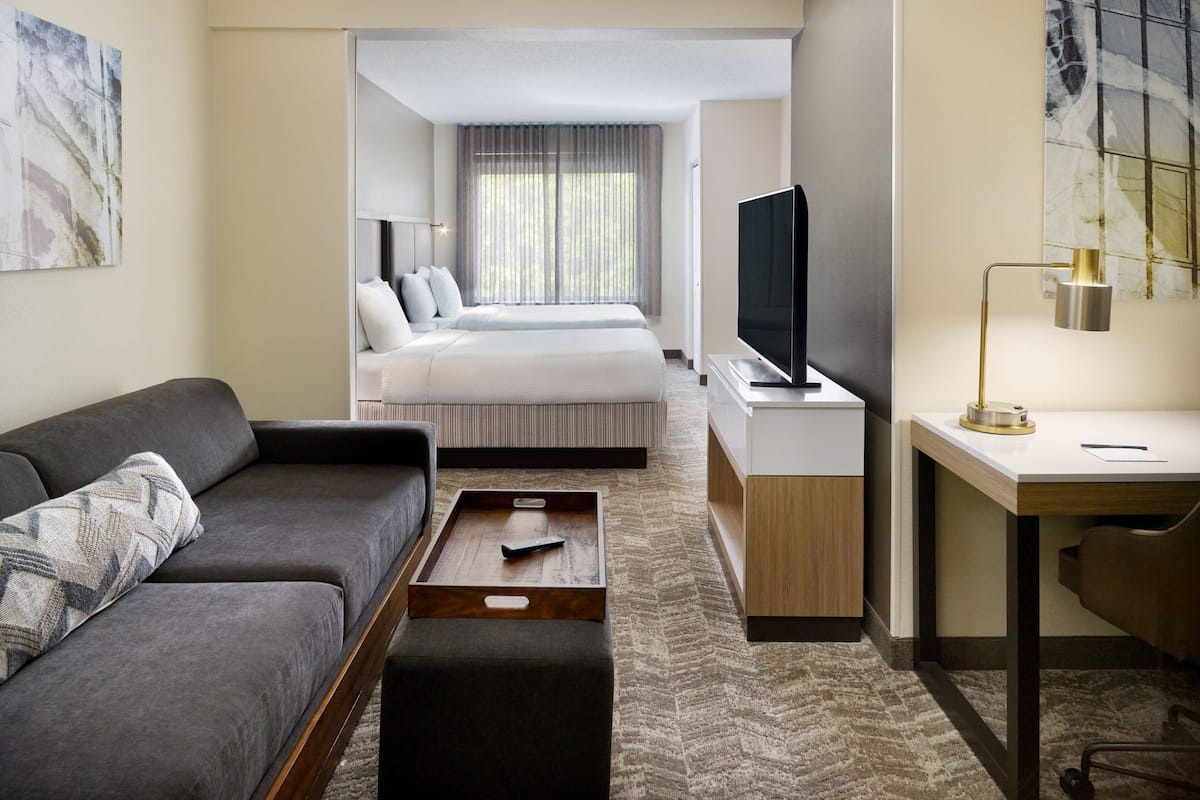 Una habitación de hotel moderna con sofá, cama, escritorio y televisión.