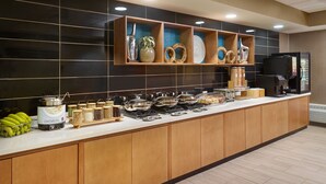 En buffet med forskellige spisemuligheder, en kaffemaskine og et køleskab.