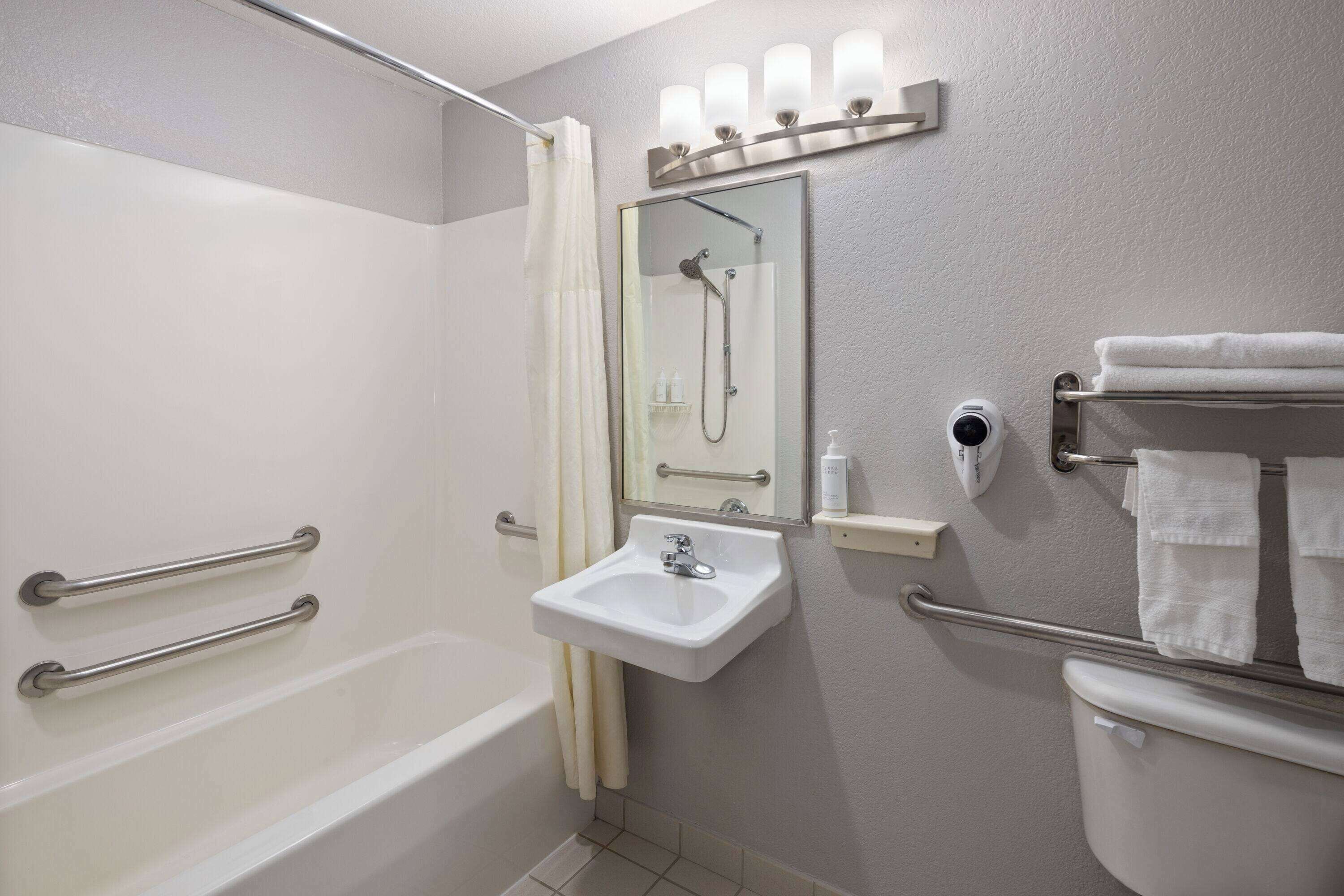A bathroom with a bathtub, a sink, a mirror, and a toilet.