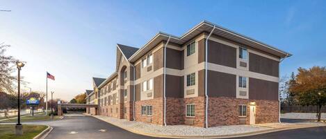A multi-story hotel with a brick facade, a flat roof, and a parking lot.