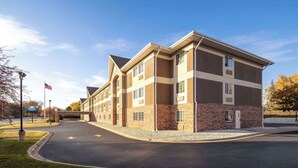 A multi-story hotel with a brick facade, large windows, and a flat roof. - Days Inn & Suites by Wyndham Green Bay WI. (Green Bay)