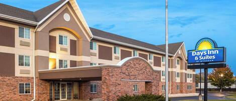 A Days Inn & Suites building with a brick facade, large windows, and an American flag.