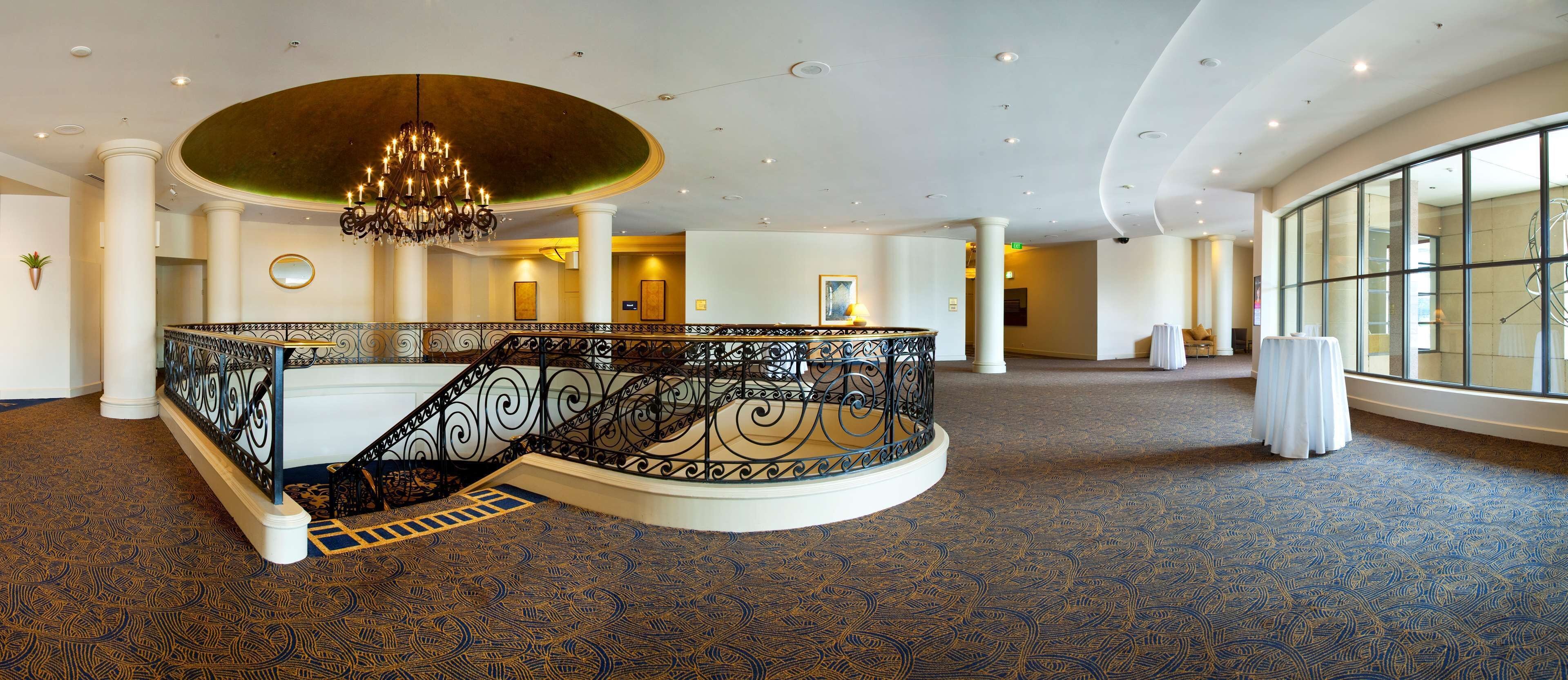 A grand interior with a central staircase, large windows, and a chandelier.