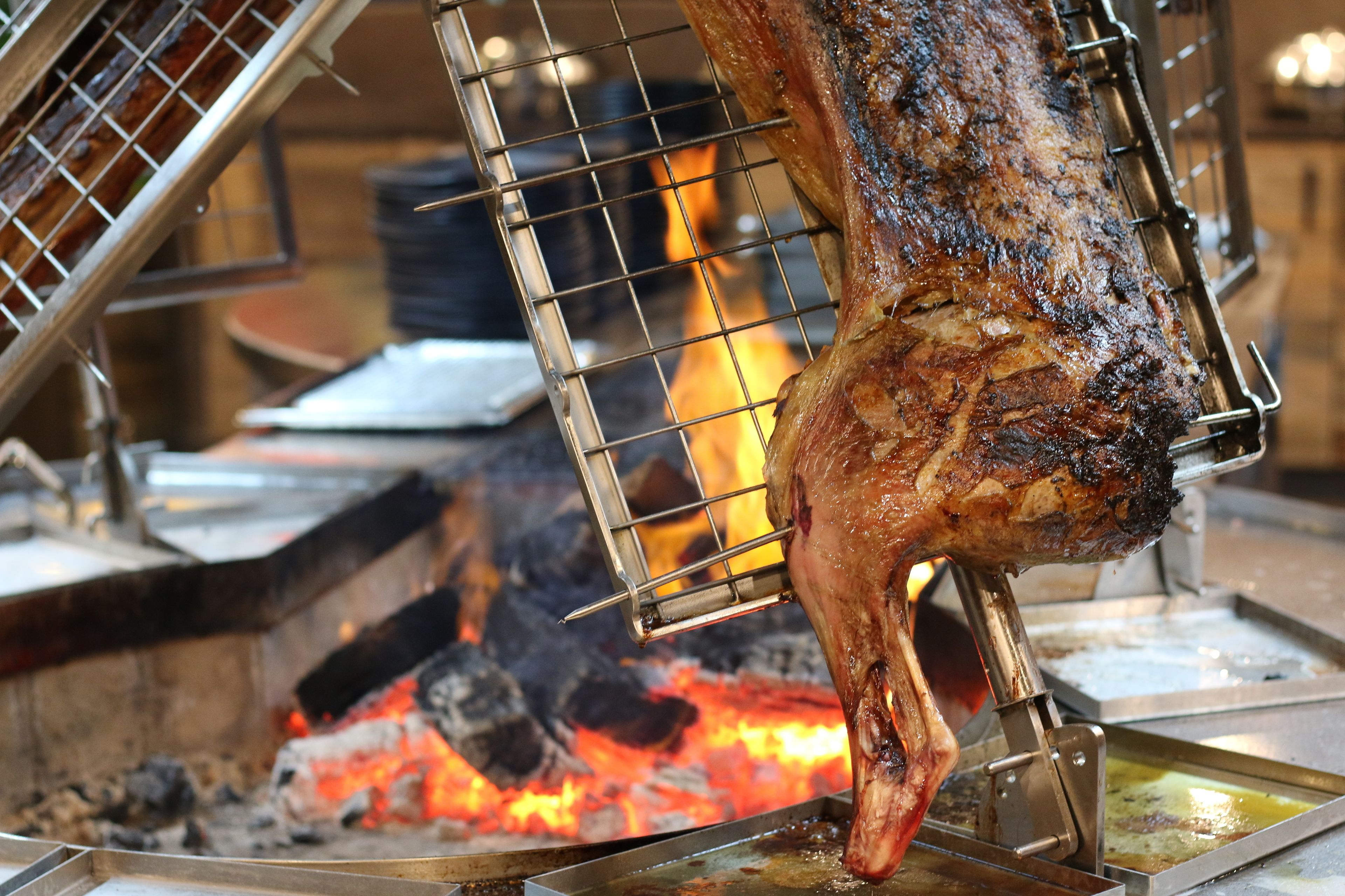 A large, roasted meat on a spit over an open flame.