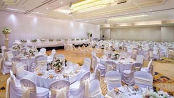 A banquet hall with round tables, white tablecloths, and chairs with white sashes.