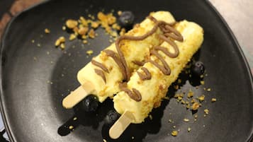 Two ice cream bars on a black plate with crumbs and a wooden stick.