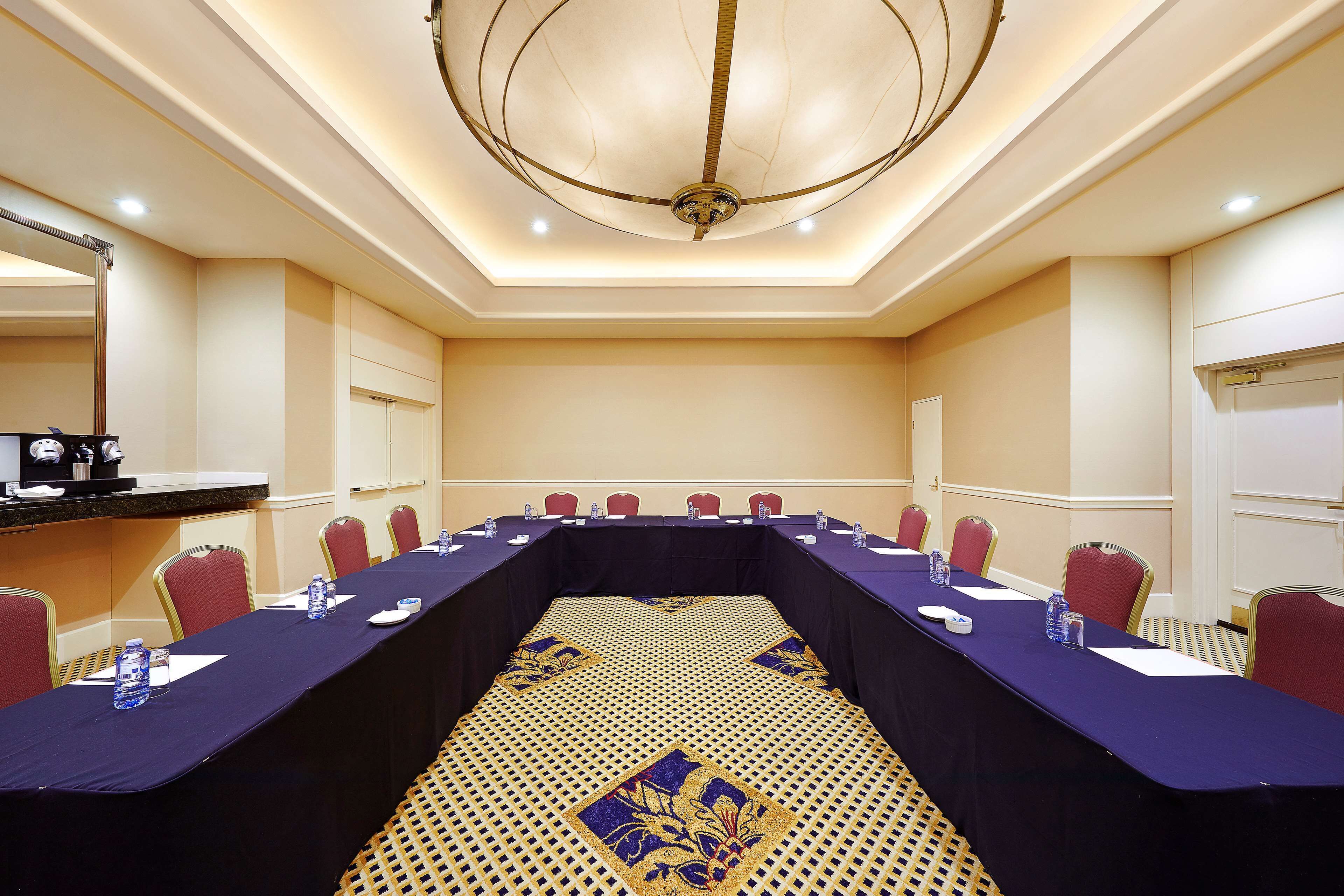 A conference room with a long table, red chairs, and a chandelier.