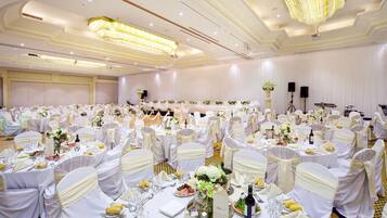 A banquet hall with round tables, white tablecloths, and chairs with white sashes.