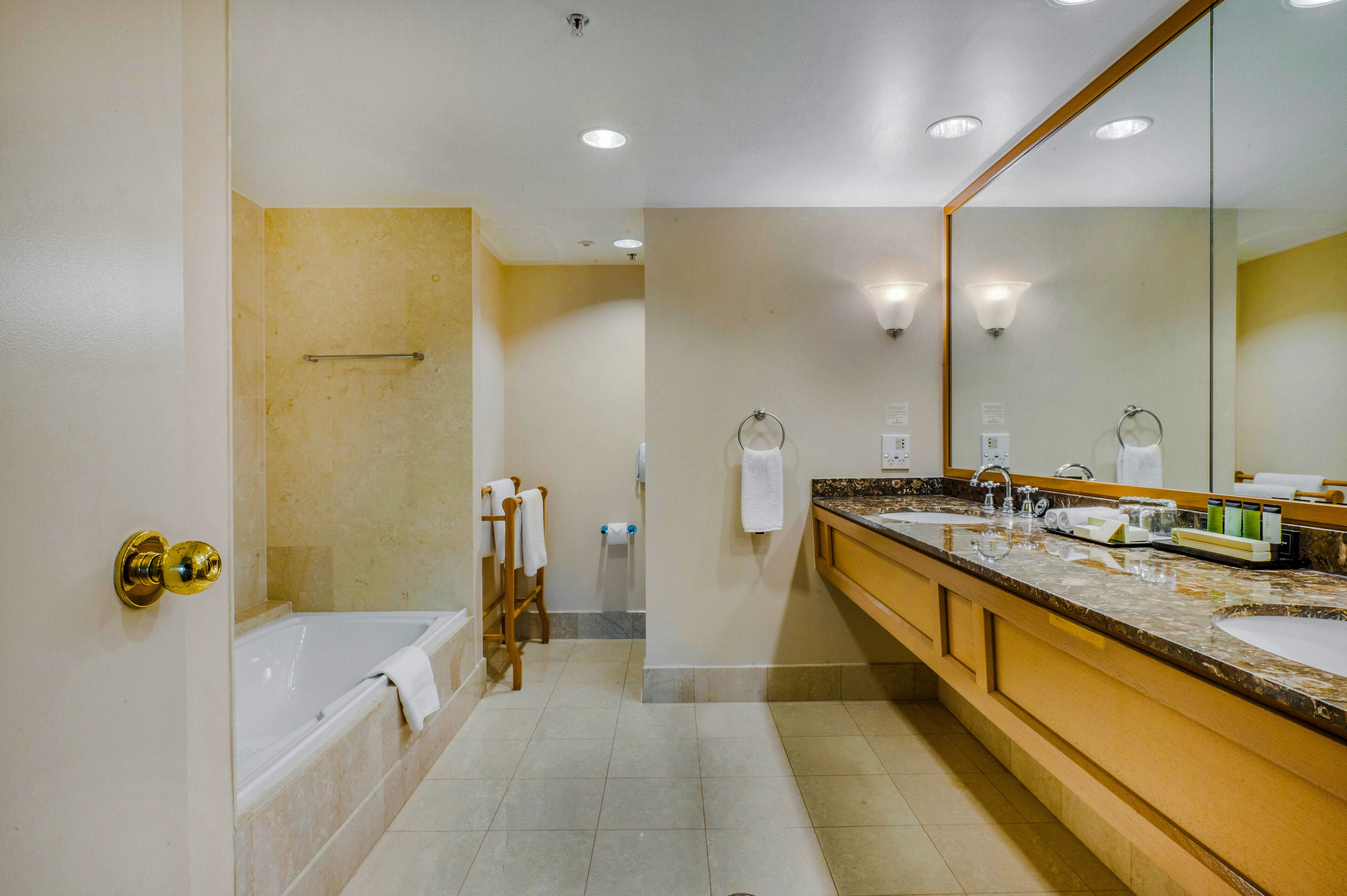 Ein Badezimmer mit Badewanne, großem Spiegel, Doppelwaschbecken und Handtuchhalter.