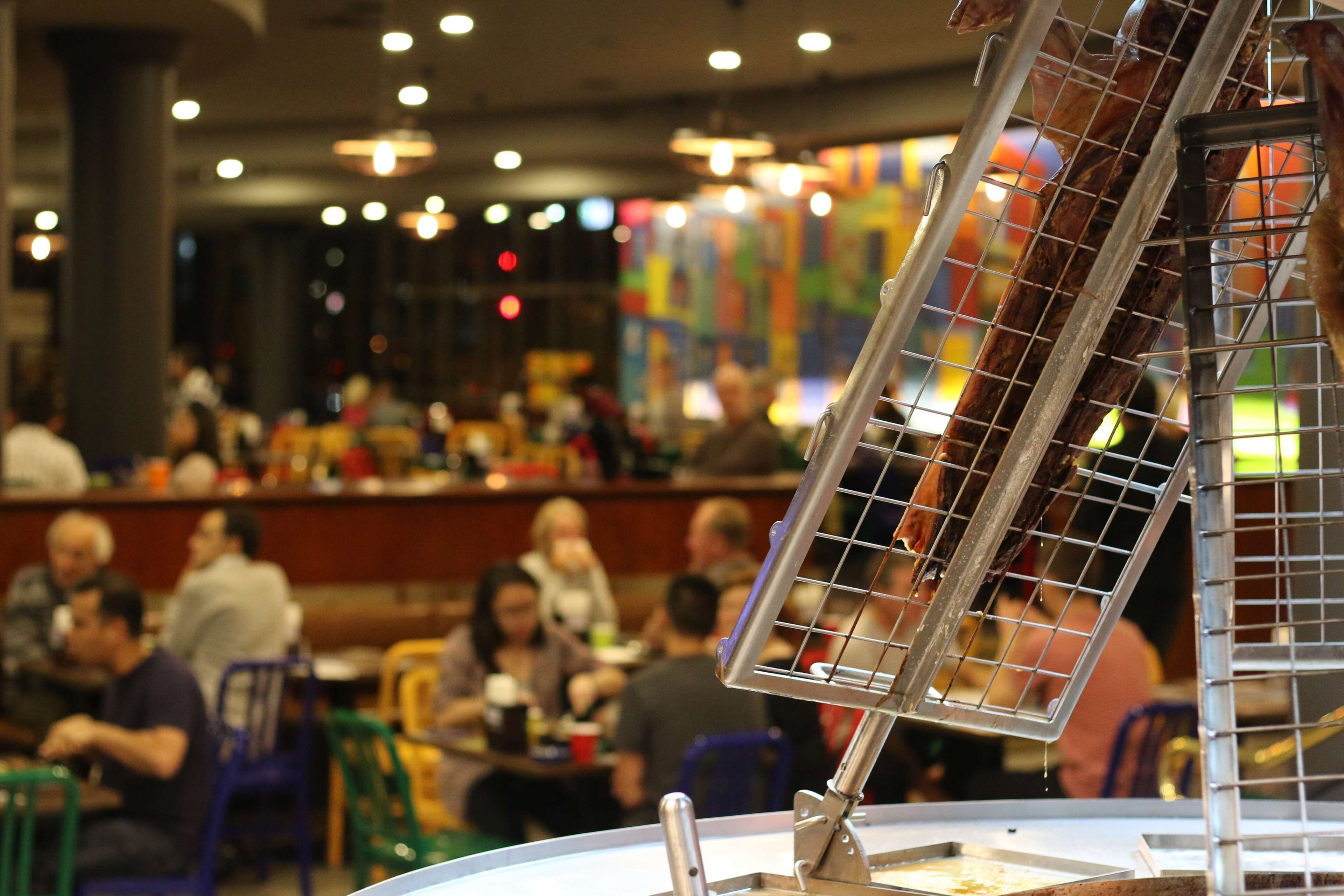 A restaurant interior with tables and chairs, a counter, and a hanging light fixture.