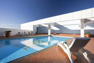 Una piscina con sillas de descanso y plantas en macetas.