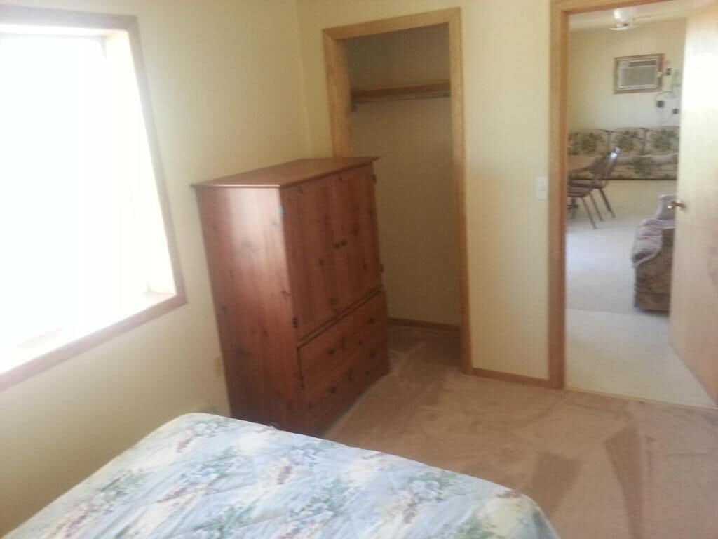 A bedroom with a bed, a wooden dresser, and a closet.