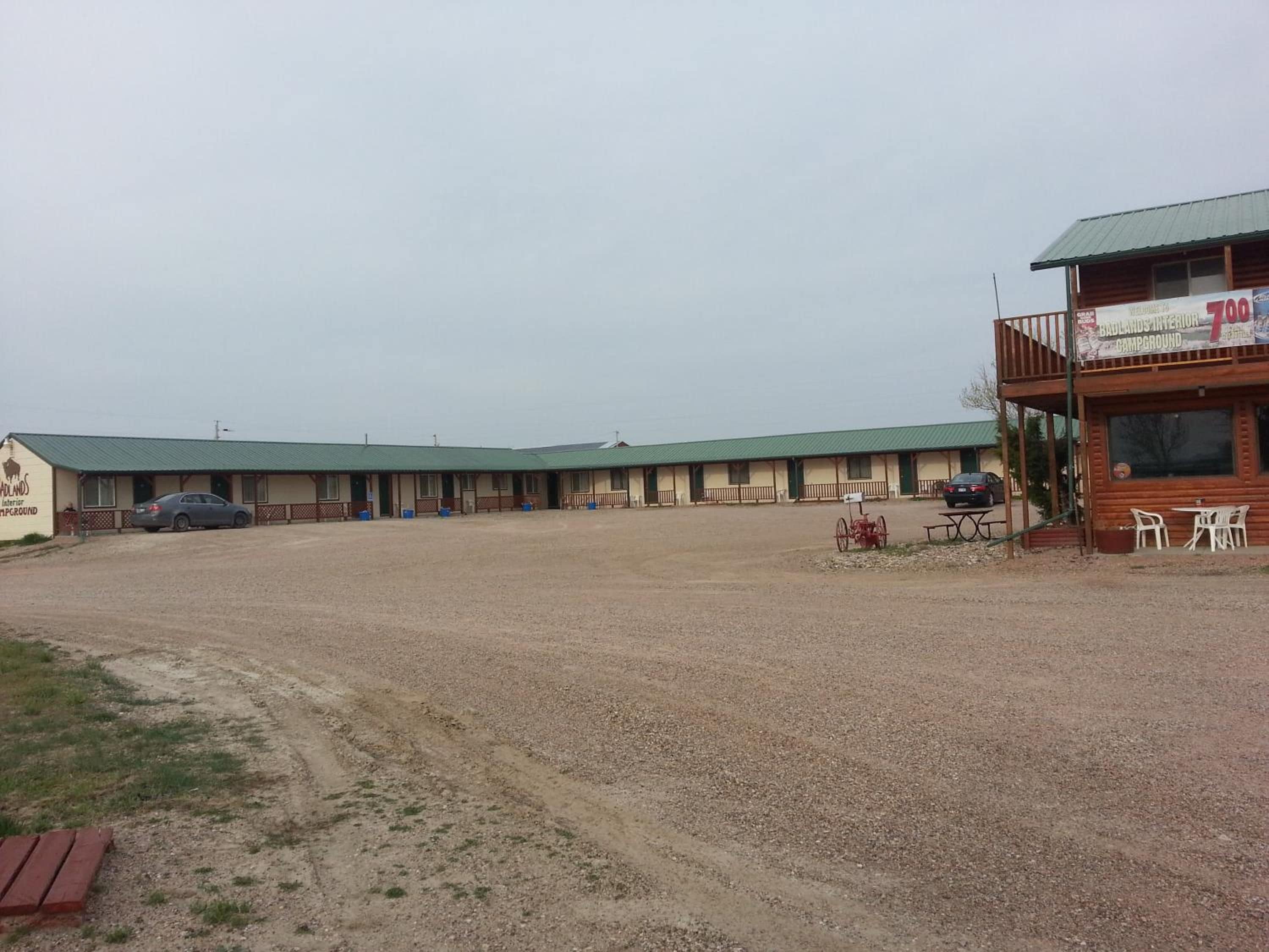 A motel with multiple rooms, a covered parking area, and a small outdoor seating area.
