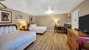 Une chambre d’hôtel avec deux lits, un bureau, une chaise, une commode et un téléviseur.