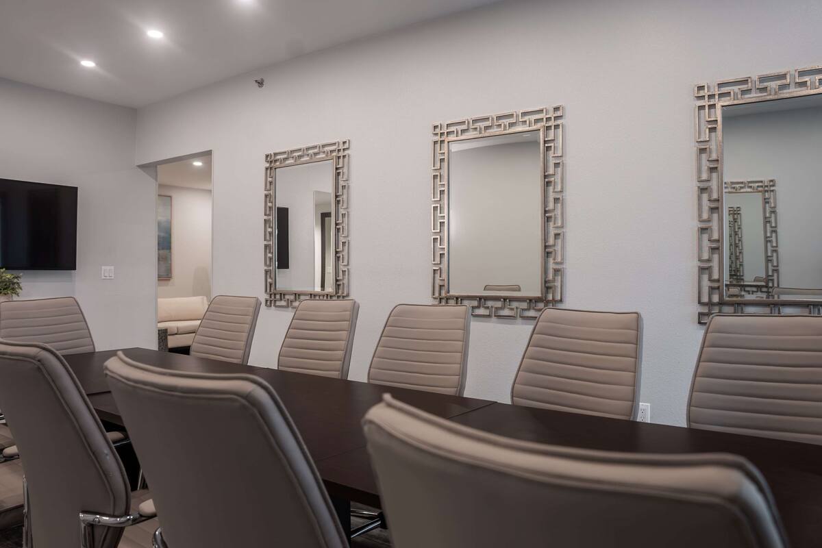 Uma sala de conferências com uma mesa comprida e seis cadeiras, três de cada lado.