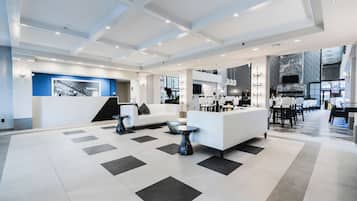A spacious lobby with a reception desk, seating area, and a kitchen in the background.